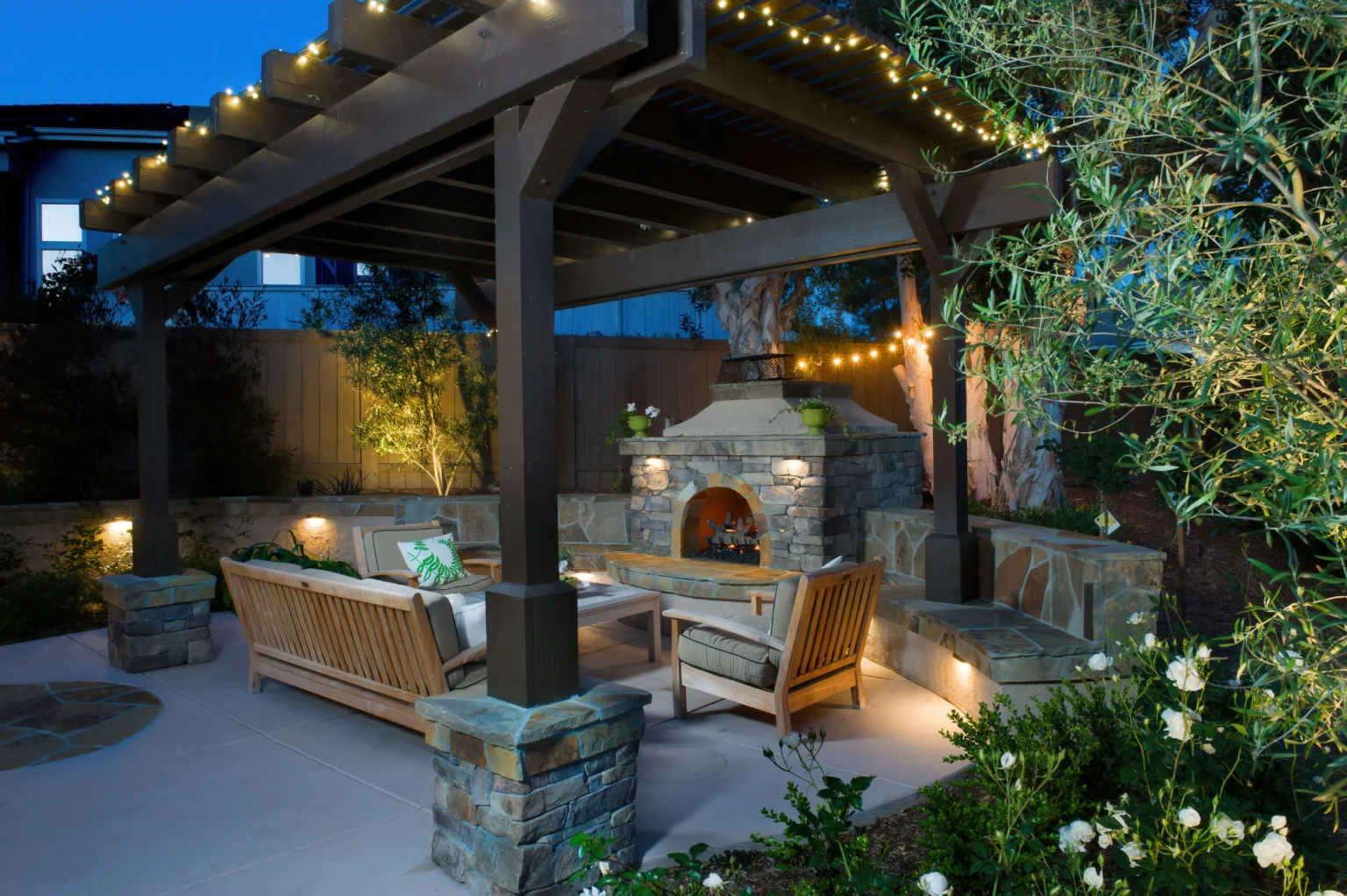 Covered pavilion with a stone fireplace and lighting at night